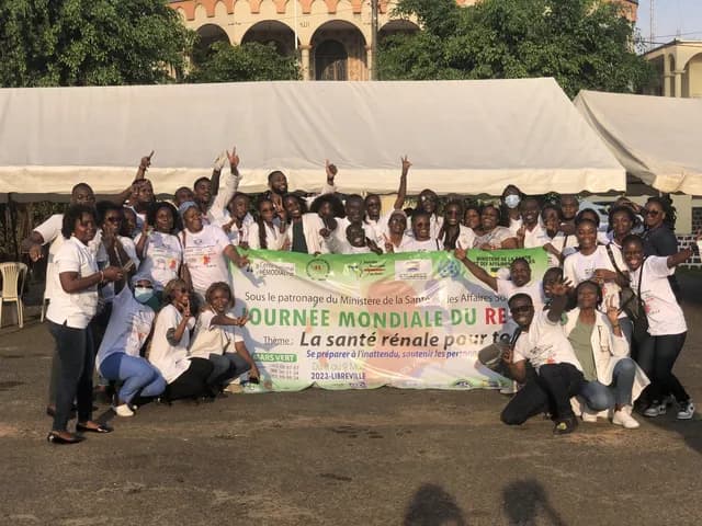 Grand groupe de soignants et de bénévoles en t-shirts blancs autour de la banderole de la Journée mondiale du rein 2023, à Libreville