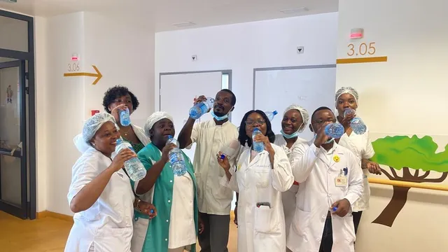 Health workers in white coats drinking water in a hospital corridor