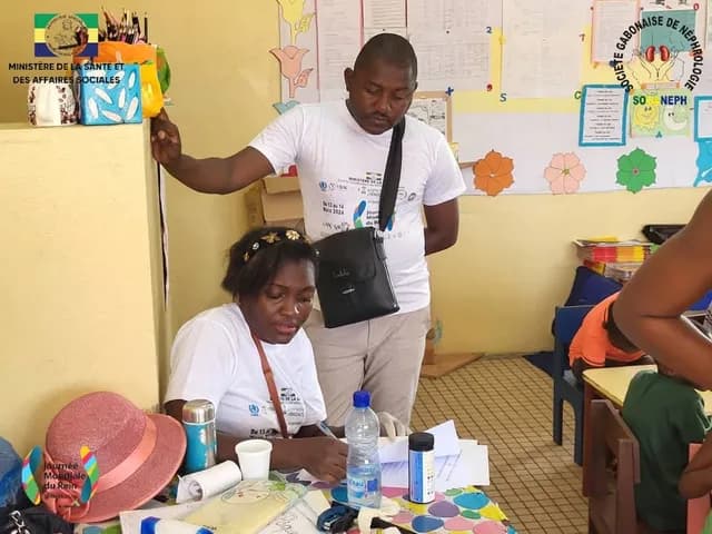 Screening in a classroom, World Kidney Day 2024: a volunteer fills in a form next to a team member