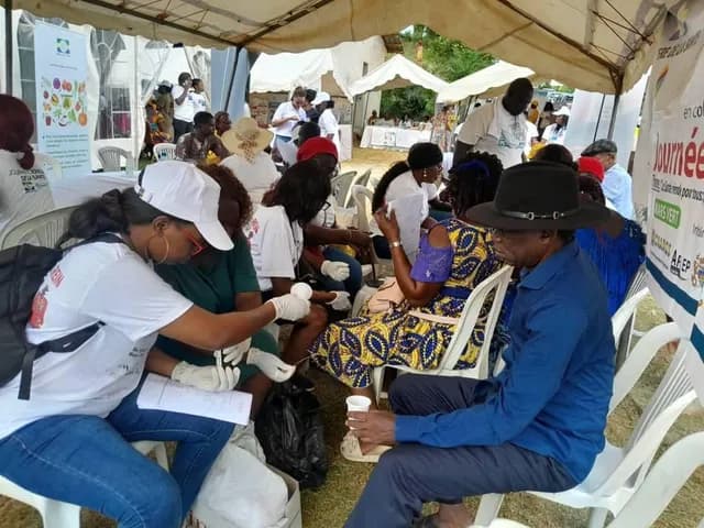 Volunteers in white T-shirts and caps screening visitors under the tents, World Kidney Day 2024