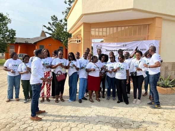 Volunteers in white T-shirts in front of the World Kidney Day banner