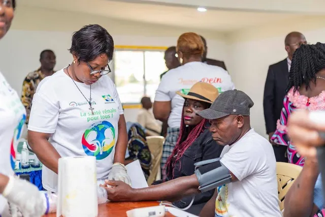 A volunteer in a “Kidney health for all” T-shirt measures a visitor’s blood pressure
